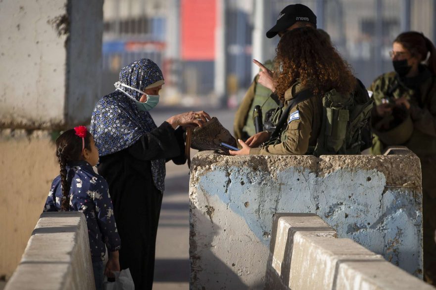 Illustrative: Israeli soldiers check a Palestinian woman as she waits to cross the Qalandiya checkpoint between the West Bank city of Ramallah and Jerusalem, April 23, 2021. (AP/Majdi Mohammed)